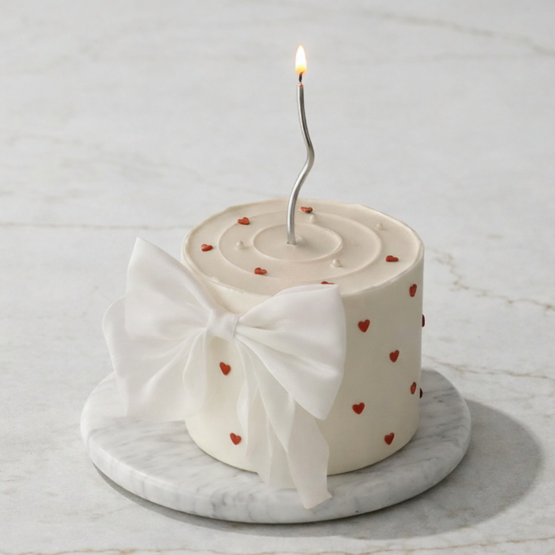 Small cake with a single lit candle on a marble surface