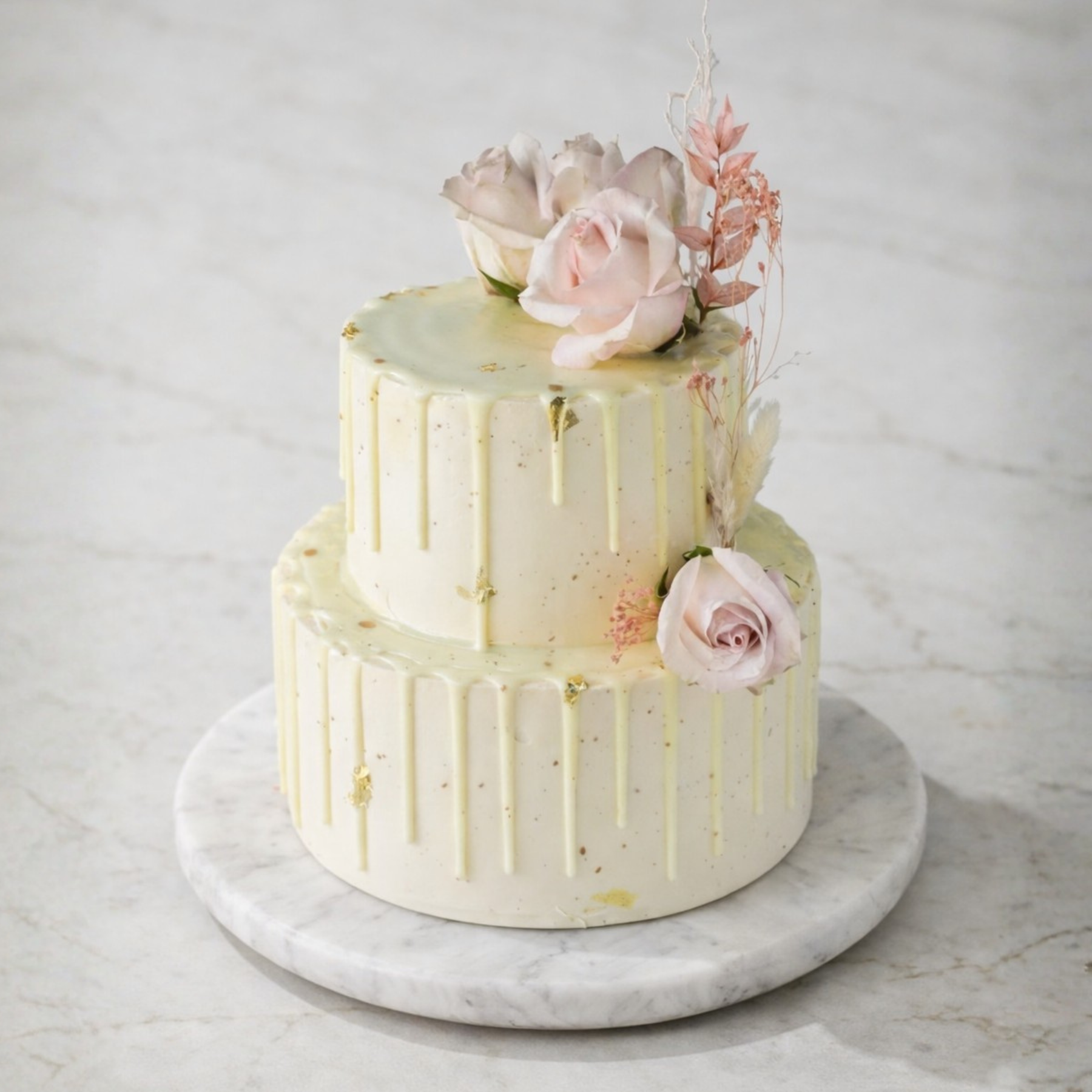 Two-tiered cake with floral decorations on a marble surface