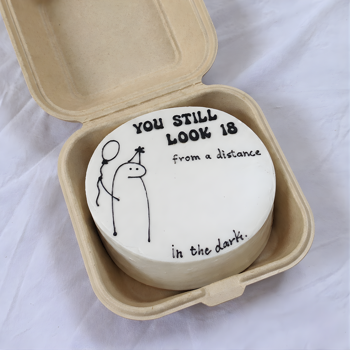 Round white object with text and drawing in a cardboard container on a light background