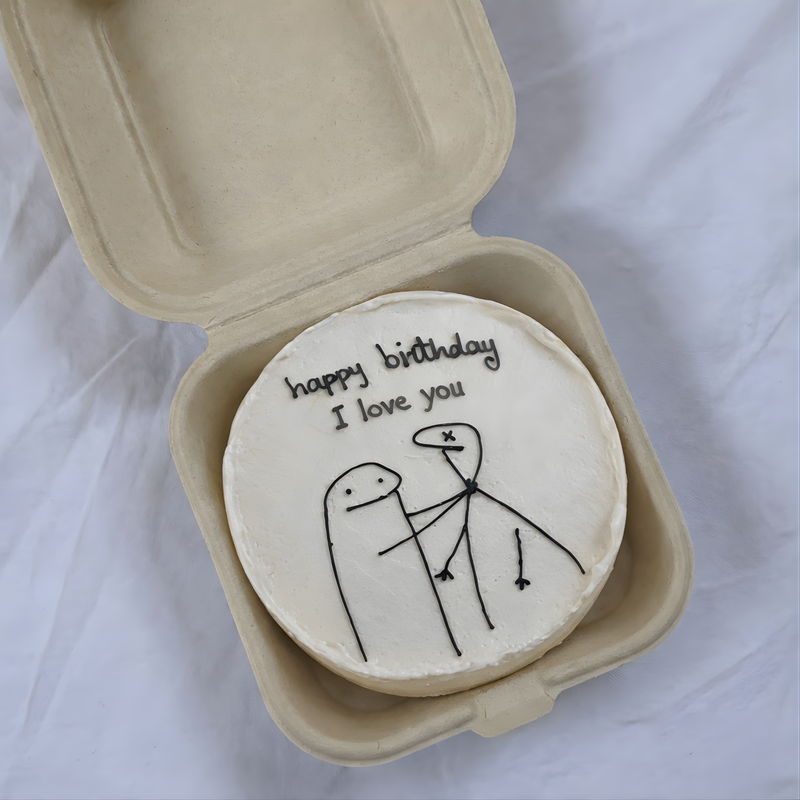 Small round cake with 'happy birthday I love you' text in a cardboard box on a white background