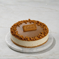 Rustic Biscoff cake with crumb coating, caramel layer, and Biscoff piece on top, presented on a marble platter.