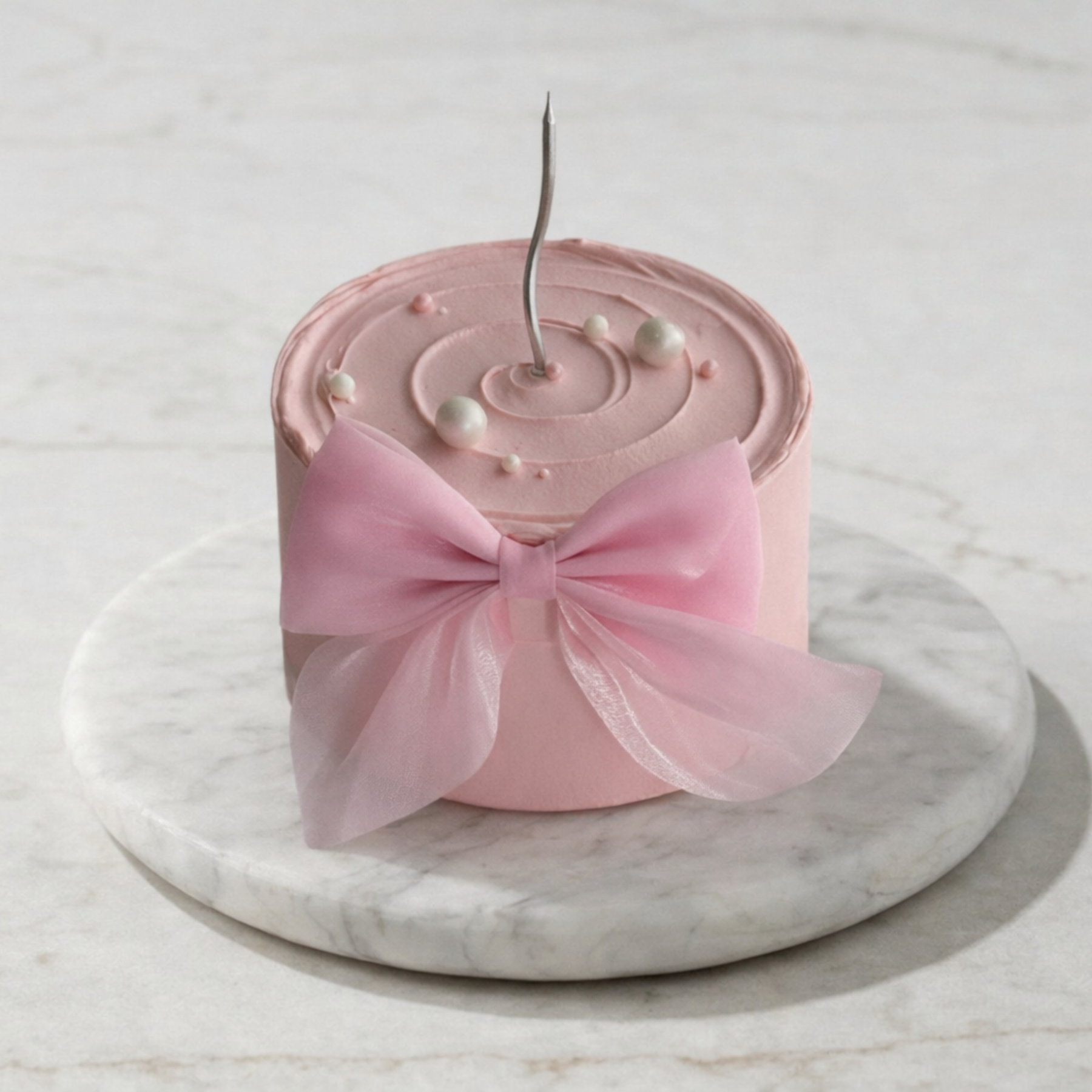 Pink cake with a decorative bow on a marble surface