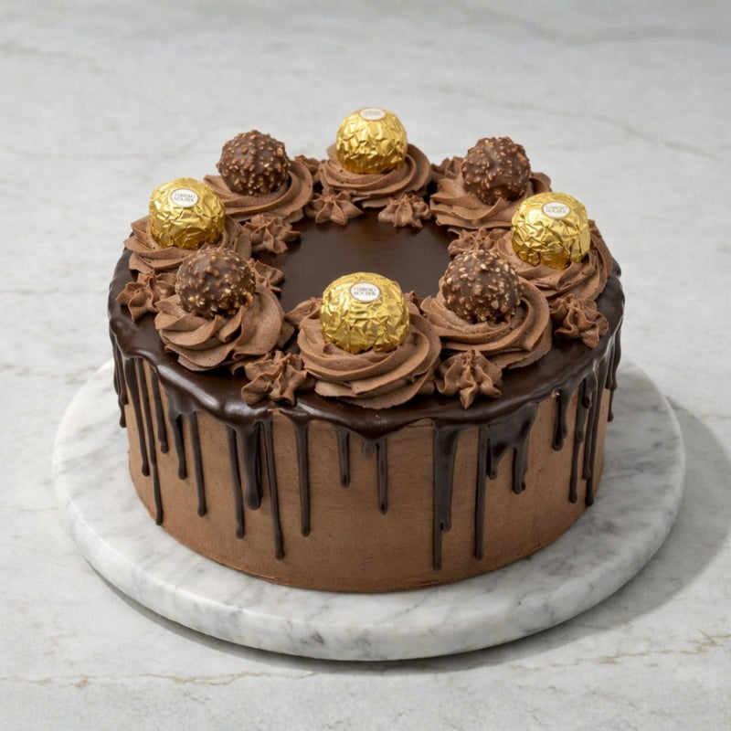 Chocolate drip cake with chocolate frosting, topped with Ferrero-style chocolates on a marble surface.