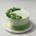 Green Ombré Cake with textured piping, adorned with green and white flowers on a marble cake stand.