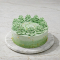 Green frosted cake with gold decorations on a marble surface