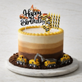 Construction-themed cake with toy trucks, chocolate dirt, yellow accents, and "Happy Birthday" topper.