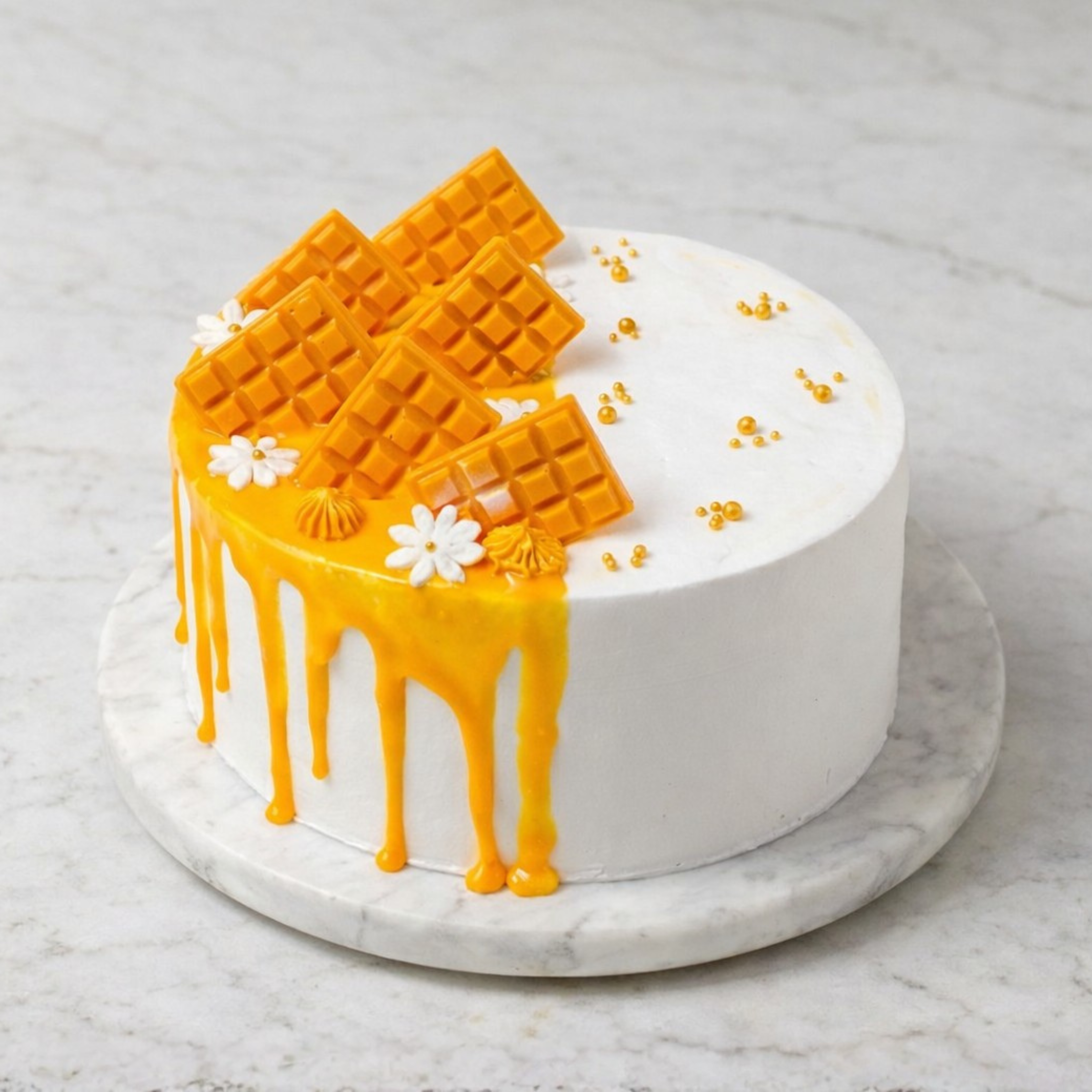 Mango Waffle Dream Cake with mango drip, waffle pieces, white flowers, and gold accents on a marble surface.