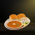 Pav Bhaji served with two buns, onions, and lemon wedges on a plate.