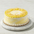 Yellow cake with white frosting on a marble stand